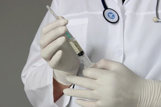 Медик набирает в шприц вакцину против энцефалита